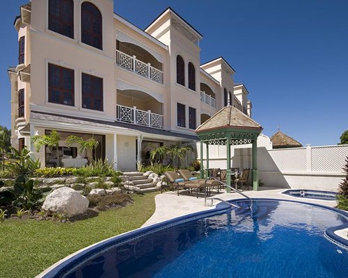 An outdoor swimming pool with chaise lounge chairs alongside the multi story unit.