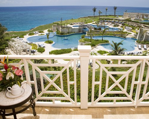 Balcony view of an outdoor swimming pool alongside the ocean.