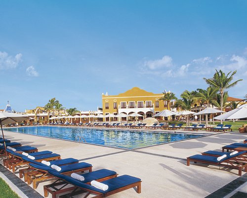 An outdoor swimming pool with chaise lounge chairs and sunshades alongside the resort unit.