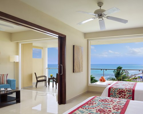 A well furnished bedroom with two beds alongside living area with the beach view.