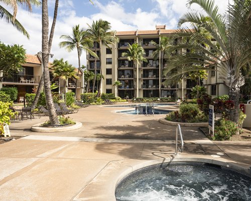 A scenic outdoor swimming pool with chaise lounge chairs and trees alongside resort units.