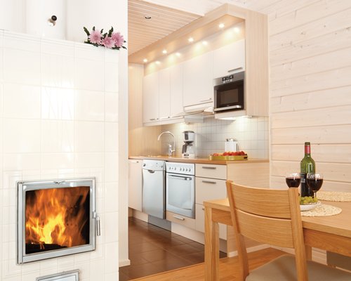 An open plan kitchen and dining area with fire in the fireplace.