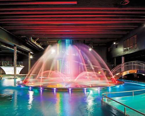 A view of an indoor swimming pool with a dancing fountain.