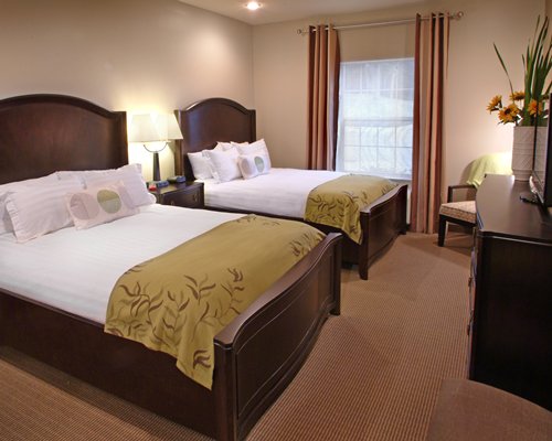 A well furnished bedroom with two beds and a television.