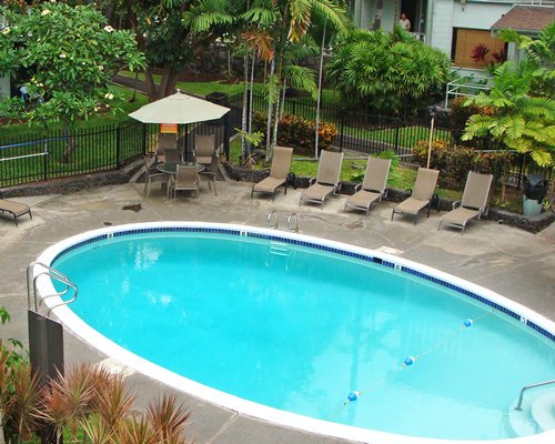 An outdoor swimming pool with chaise lounge chairs alongside trees.