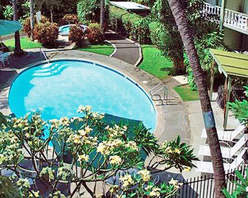 An outdoor swimming pool and hot tub with chaise lounge chairs and sunshades.