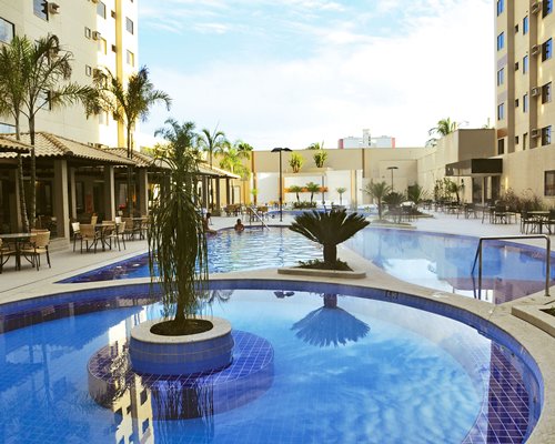 An outdoor swimming pool with patio furniture and landscaping alongside the resort.