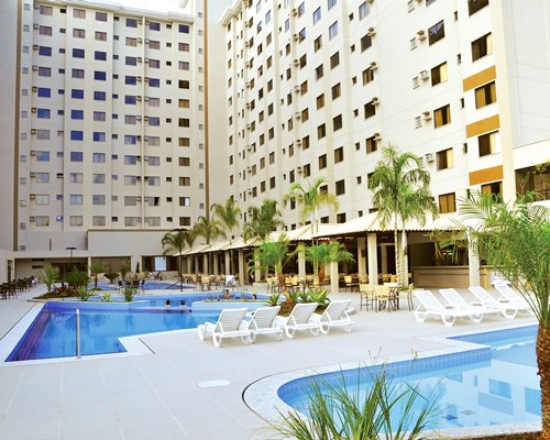 View of outdoor pools with chaise lounge chairs alongside the multi story condo.