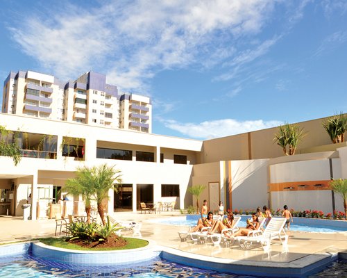 A view of outdoor swimming pools for adults and children with chaise lounge chairs alongside the resort units.