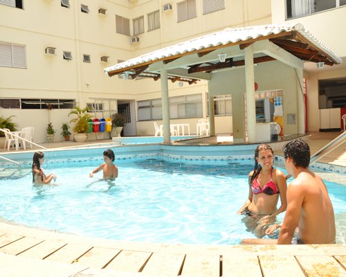 People at an outdoor swimming pool with patio chairs.