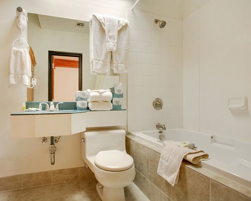 A bathroom with bathtub shower and single sink vanity.