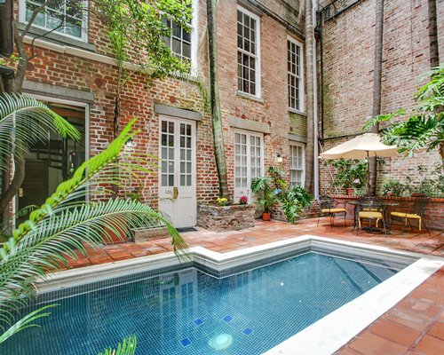 An outdoor swimming pool with patio furniture alongside multi story resort units.