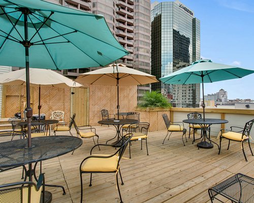 An outdoor recreation area with patio furniture and umbrellas alongside the multi story condo.