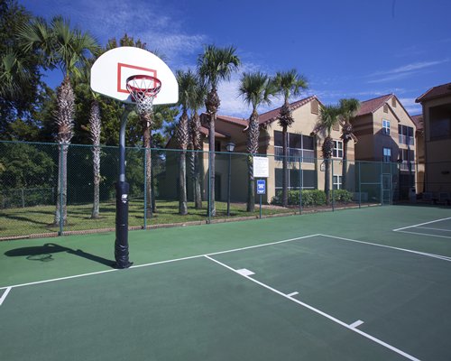 An outdoor basketball court alongside the resort units and a lawn with trees.