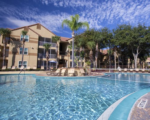 An outdoor swimming pool with chaise lounge chairs and trees alongside the resort units.