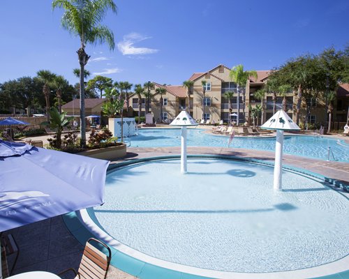 An outdoor swimming pool with patio furniture and sunshades.