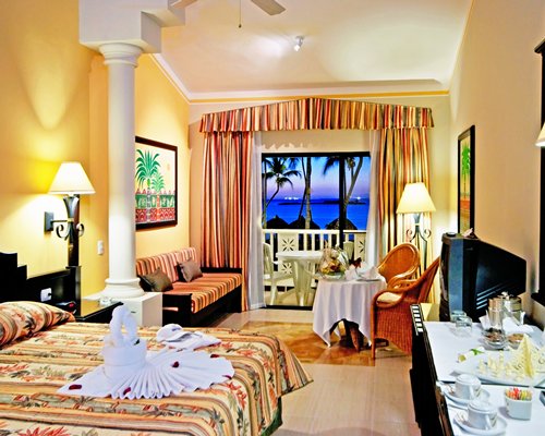 A well furnished bedroom and living area with a television and a balcony with patio.