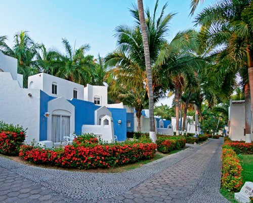 Exterior view of the resort alongside the pathway surrounded by flowering shrubs.