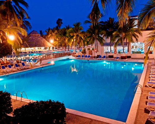 Outdoor swimming pool with chaise lounge chairs and palm trees.