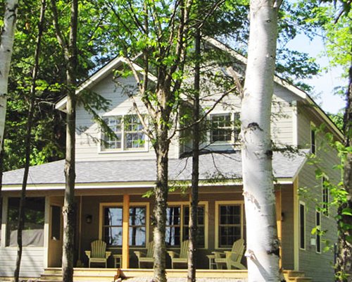 An exterior view of a resort unit with patio furniture and trees.