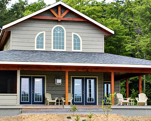 An exterior view of the cottage with patio furniture alongside the trees.