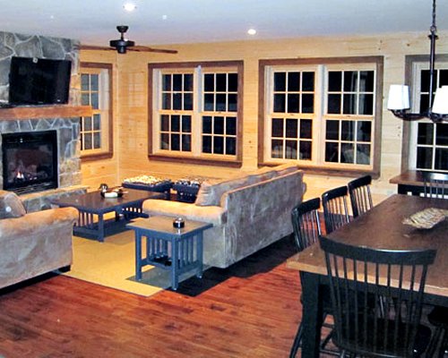 A well furnished living room with television fire in the fireplace and dining area.