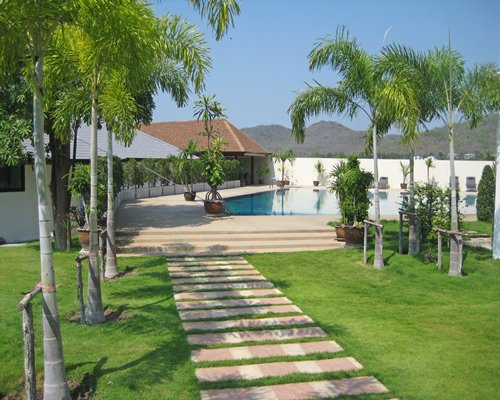 A scenic pathway with trees leading to an outdoor swimming pool.