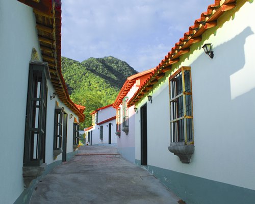 Exterior view of a pathway to units at Hotel Hacienda El Portete alongside the mountains.