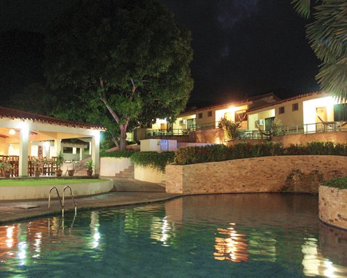 An outdoor swimming alongside the resort units at night.