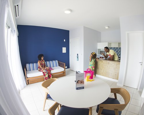 A family at a well furnished living room with balcony and beach view.