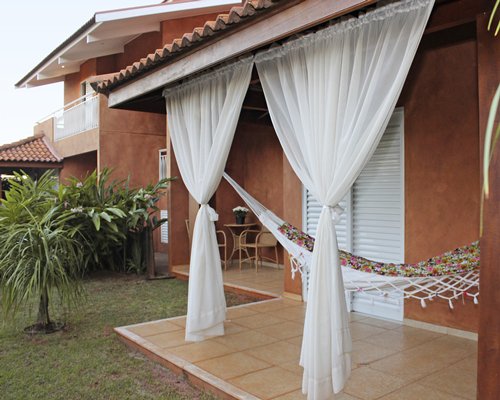 An exterior view of multi story resort units with a hammock.