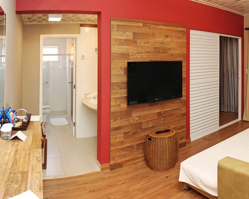 A well furnished bedroom with a television alongside a bathroom.