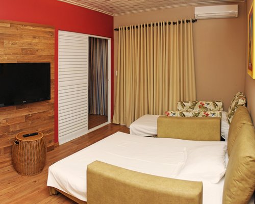 A well furnished bedroom with two double beds and a television.