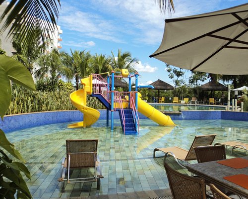 An outdoor swimming pool with the water slides chaise lounge chairs and sunshades.