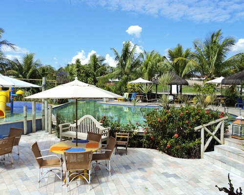 Outdoor swimming pool with outdoor dining chaise lounge chairs sunshades and slide.