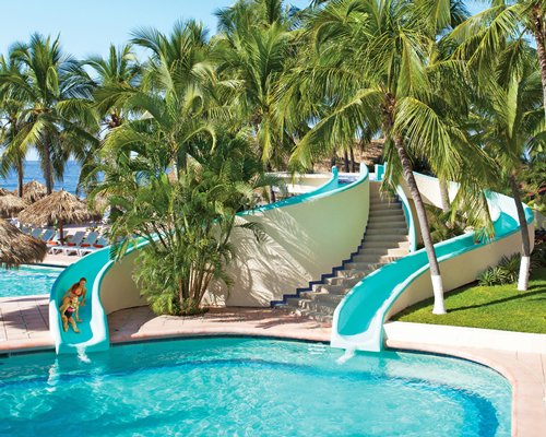 An outdoor swimming pool with water slides and trees.