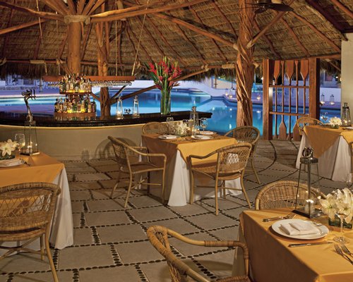 A well equipped indoor bar with dining area at dusk.
