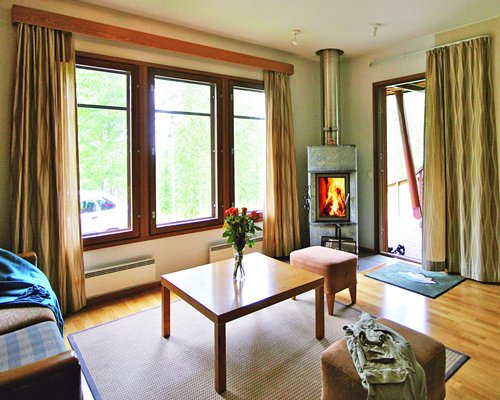 A well furnished living room with a fire in the fireplace and outside view.