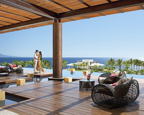 A couple in an outdoor lounge area alongside a swimming pool.
