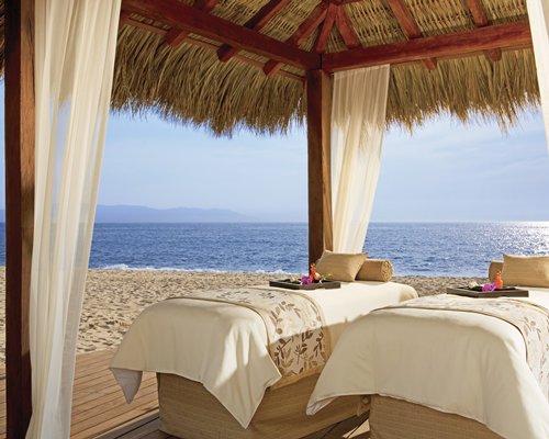 An outdoor spa with two spa beds alongside the beach.