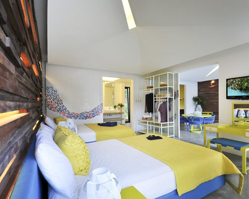 A well furnished bedroom with a television dining table and two beds.