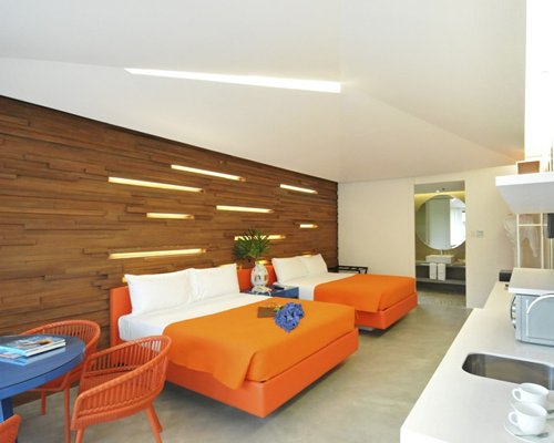 A well furnished bedroom with two beds an open plan kitchen dining area and a sink.