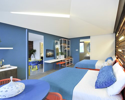 A well furnished bedroom with two beds a television and dining area.