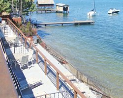Balcony with patio furniture alongside the lake with a wooden pier and boats.