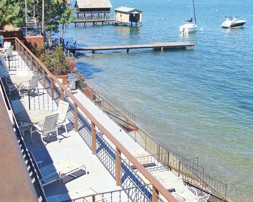 Balcony with patio furniture alongside the lake with a wooden pier and boats.