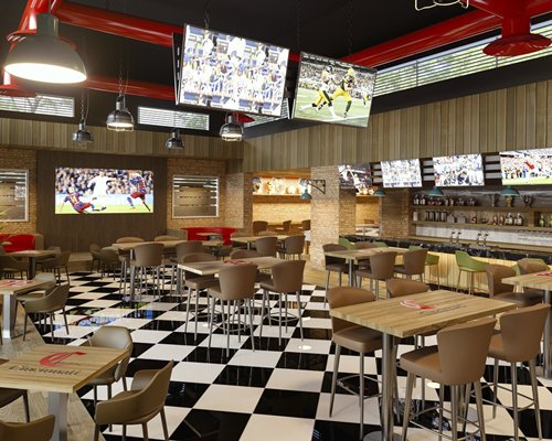 An indoor sports bar with multiple dining tables.