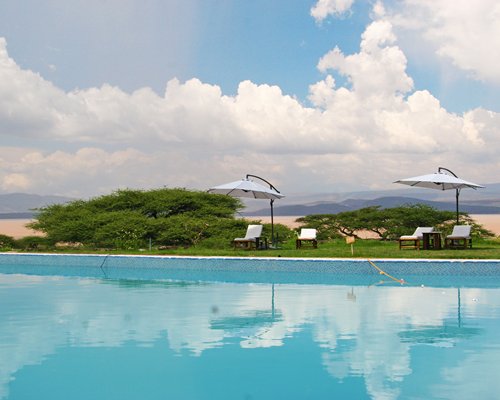 A large outdoor swimming pool with chaise lounge chairs and sunshades.