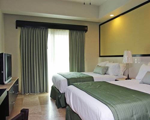 A well furnished bedroom with two beds and a television.