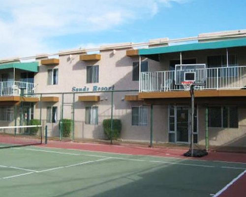 An outdoor basketball court with a tennis set up alongside resort units.