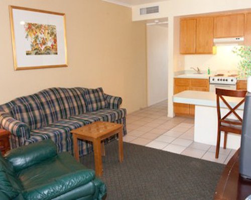 A well furnished living room with a television open plan kitchen and breakfast bar.